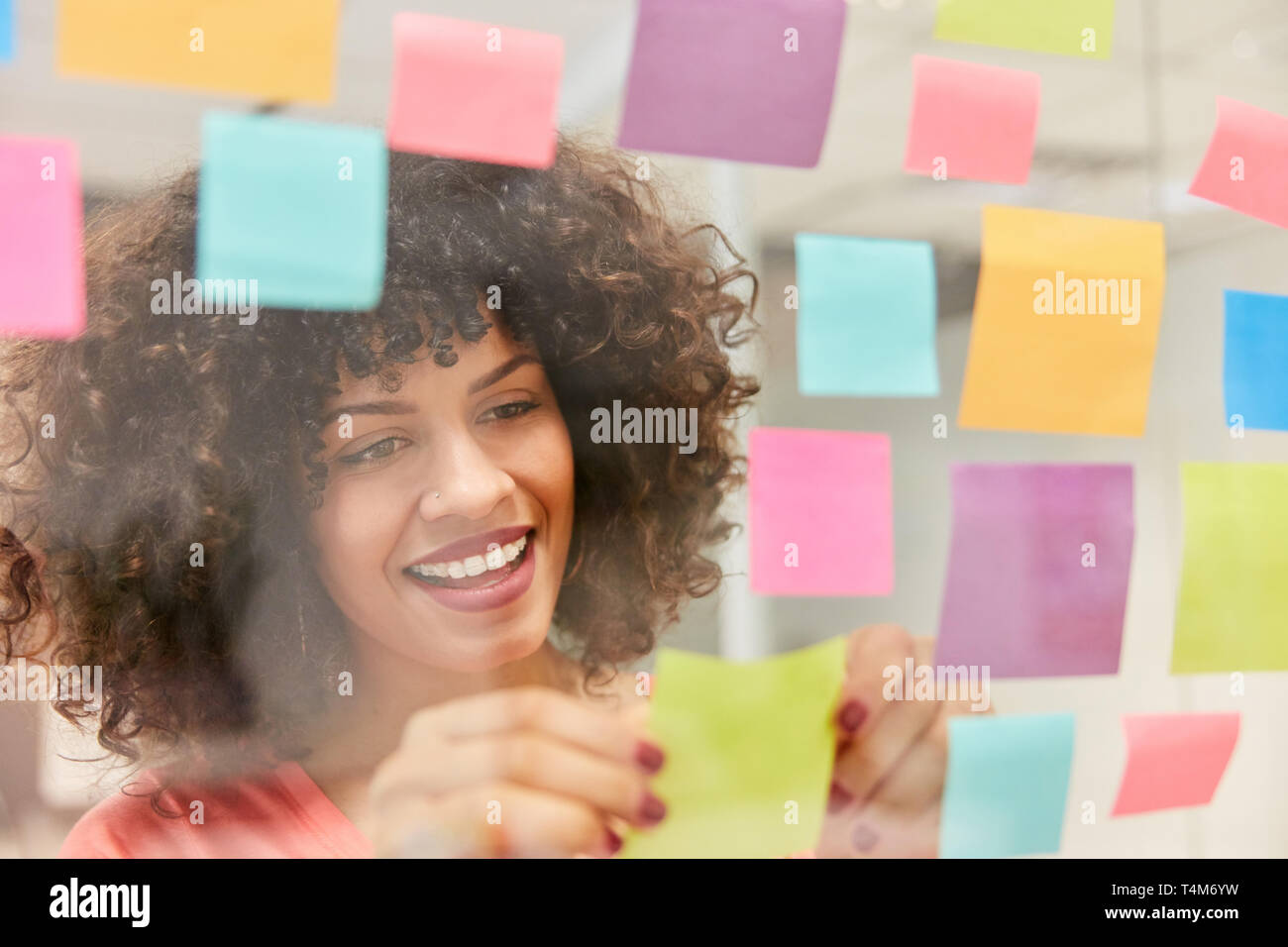 Young African businesswoman collects ideas on colorful slips while brainstorming Stock Photo