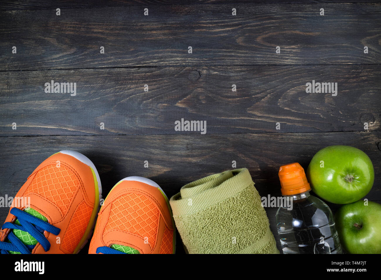 Sport shoes, apple, bottle of water and towel on wooden background. Concept healthy lifestyle, healthy food, sport and diet. Sport equipment. Top view Stock Photo
