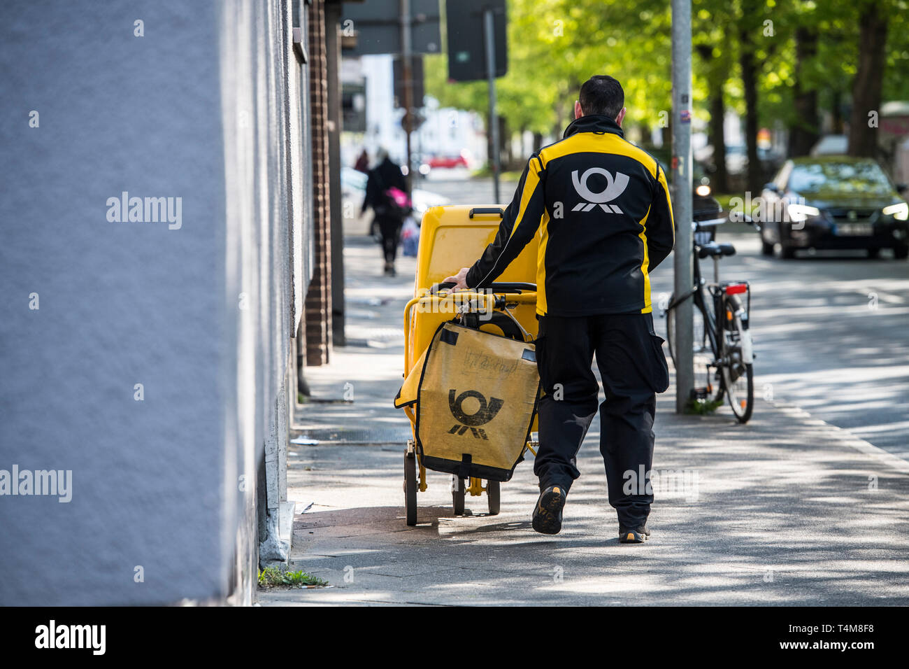 Postbote in der Großstadt zu Fuss unterwegs. Stock Photo