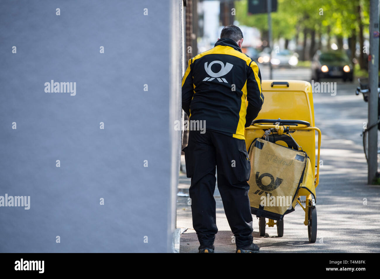 Postbote in der Großstadt zu Fuss unterwegs. Stock Photo