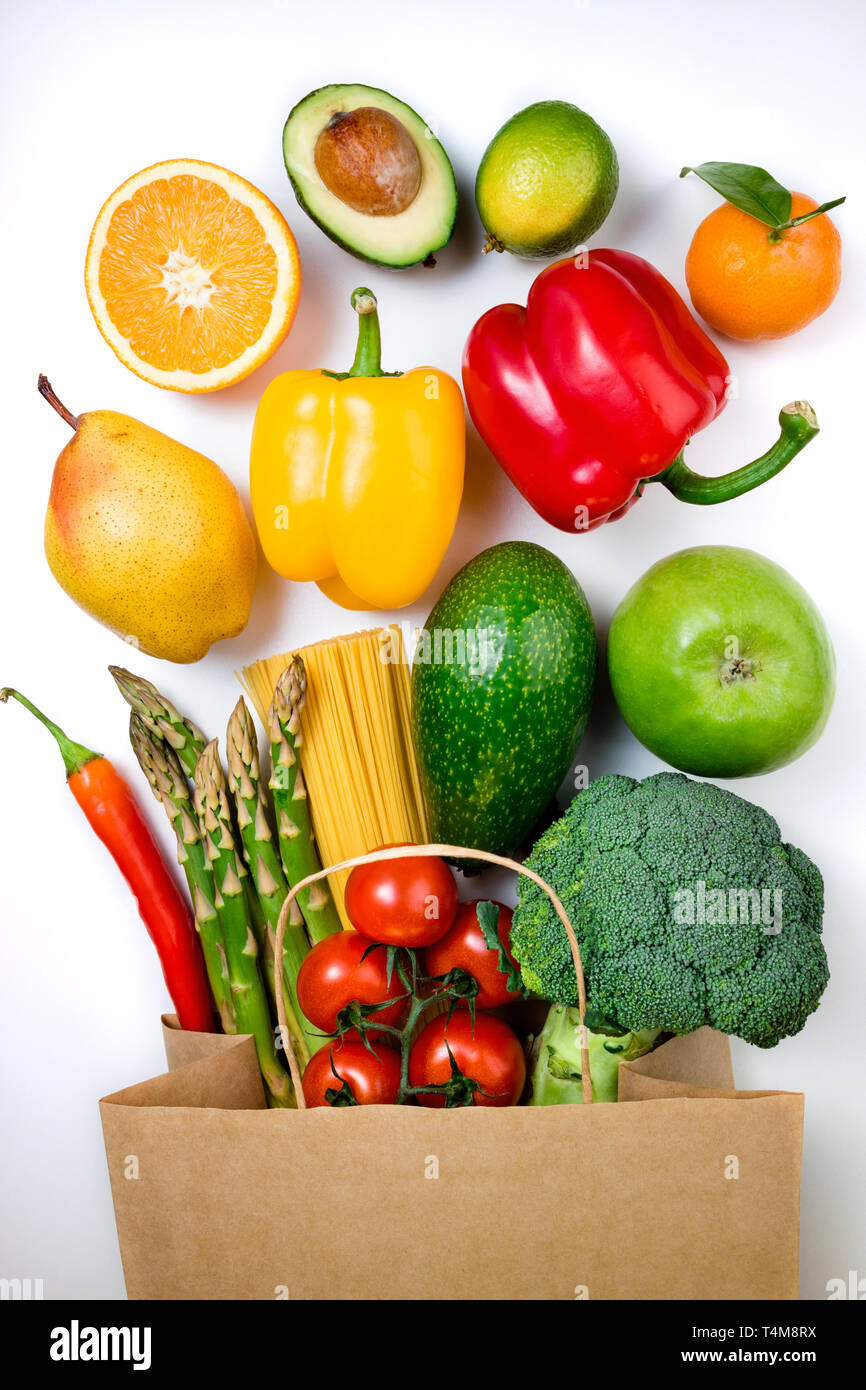 Healthy food background. Healthy food in paper bag fruits, vegetables and pasta on white background. Shopping food in supermarket, vegetarian concept. Stock Photo