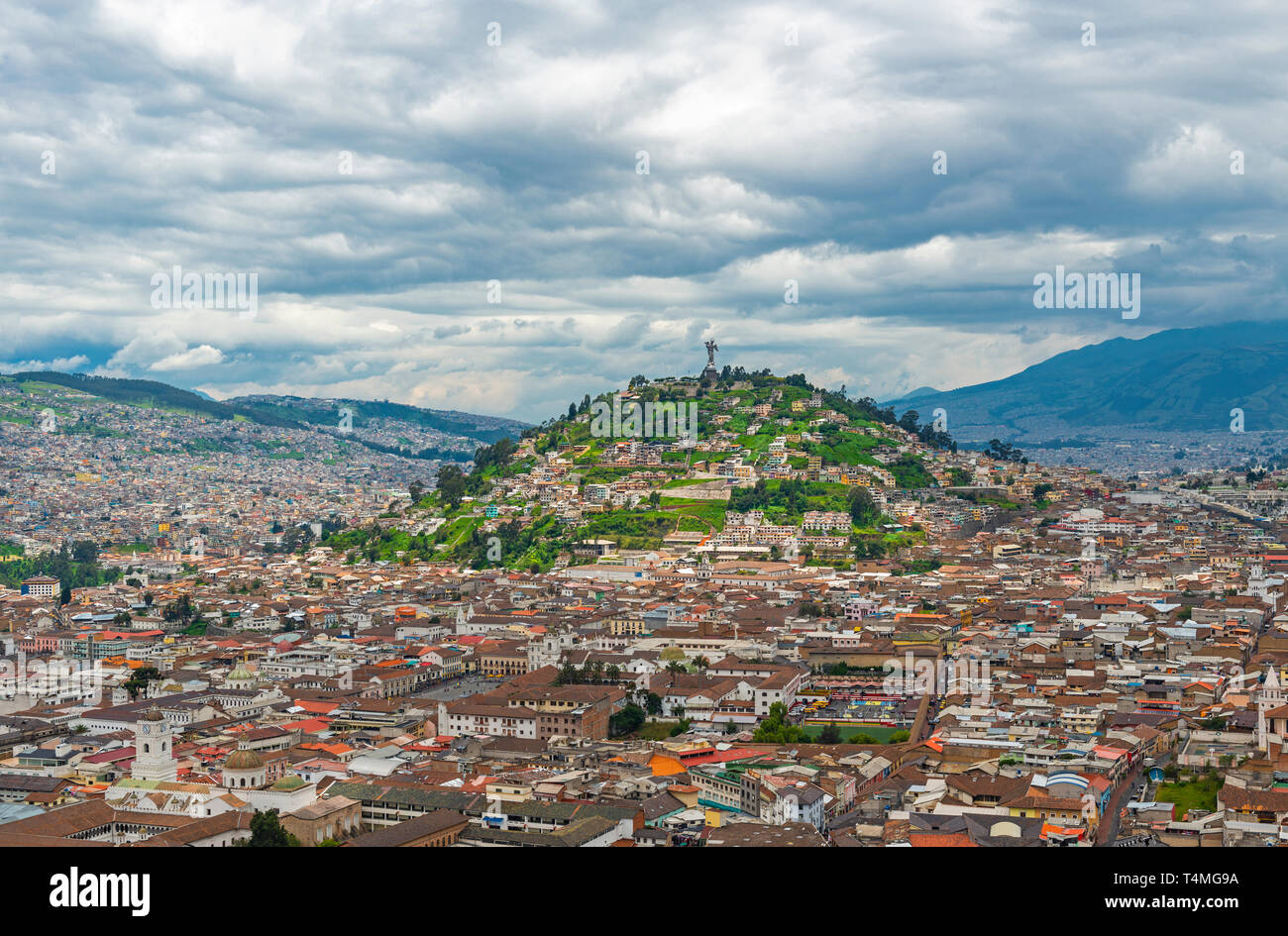 The historic city center of Quito in the Andes mountain range with the Panecillo hill and Virgin of Quito and a dramatic cloudy sky, Ecuador. Stock Photo