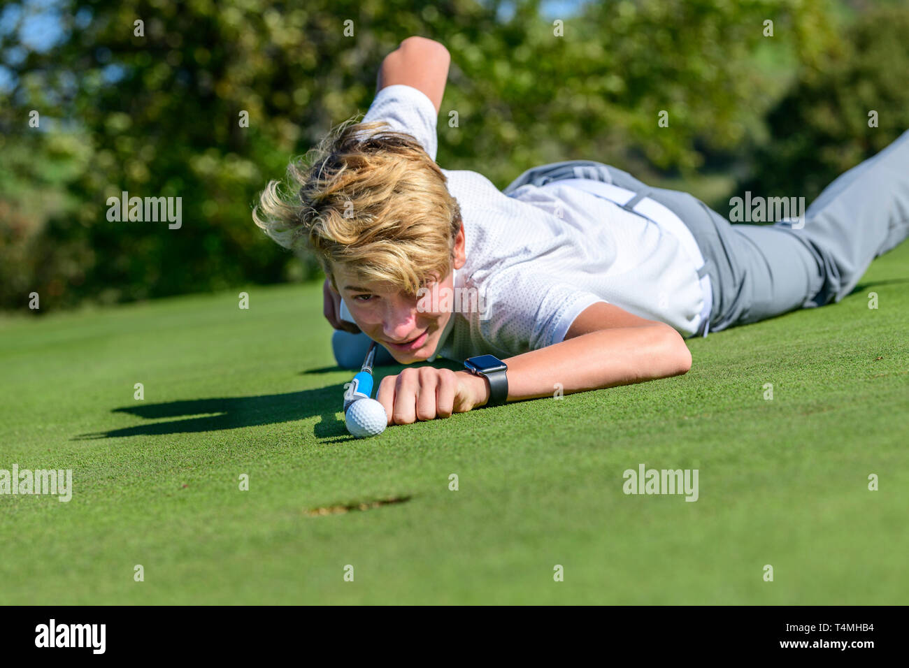 Unconventional putting - young golfer putting ball like a billiard player Stock Photo