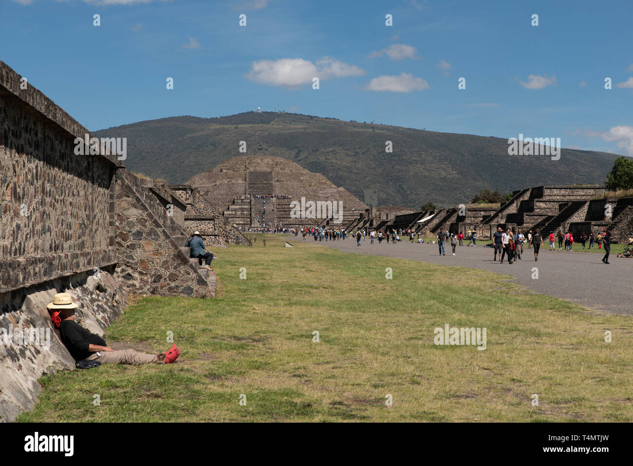 A tourist sleeps in the pyramid alley in Teotihuacan with pyramid of the moon in the background, Mexico. Stock Photo