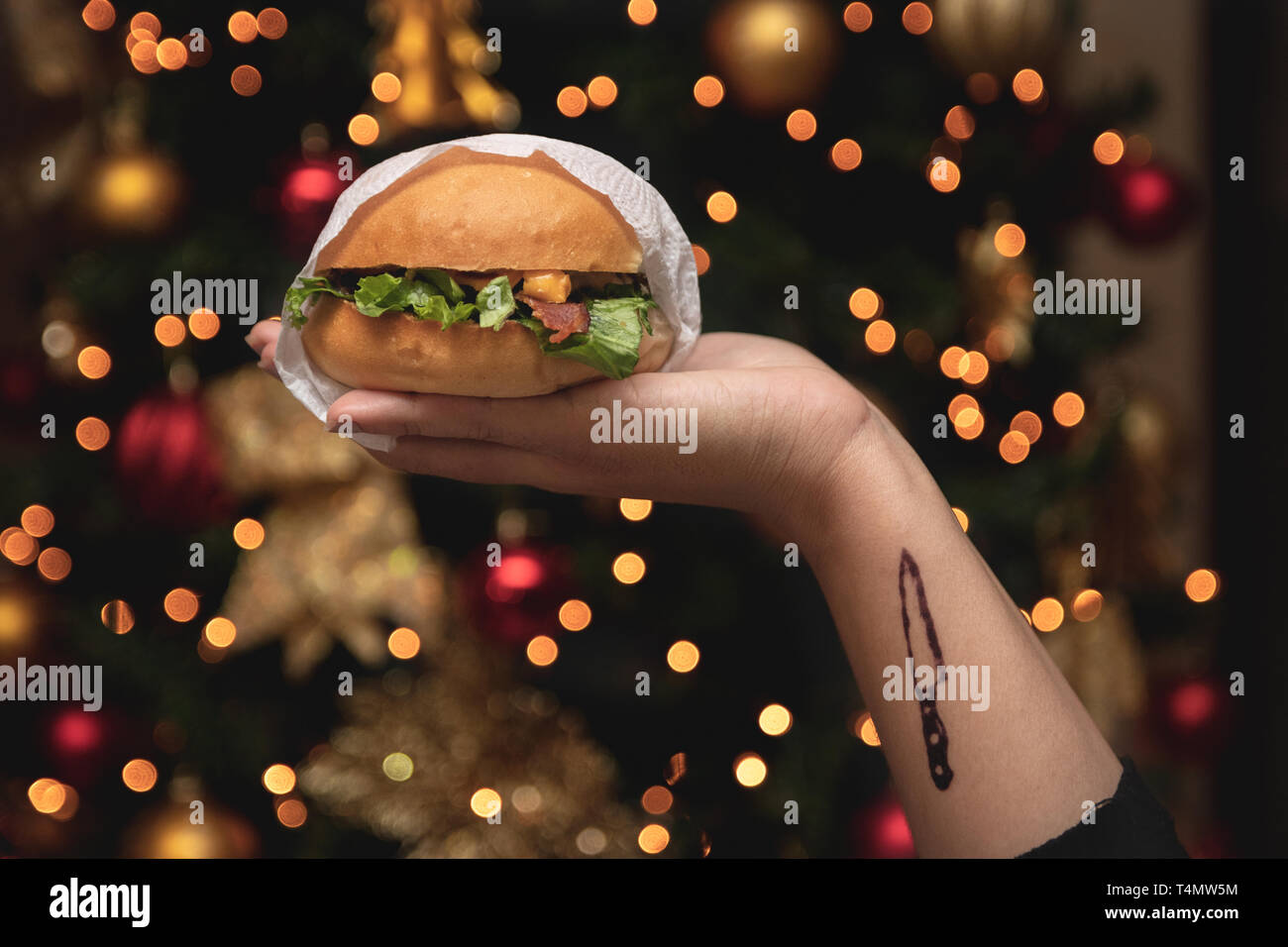 hand holding a burger with christmas background Stock Photo