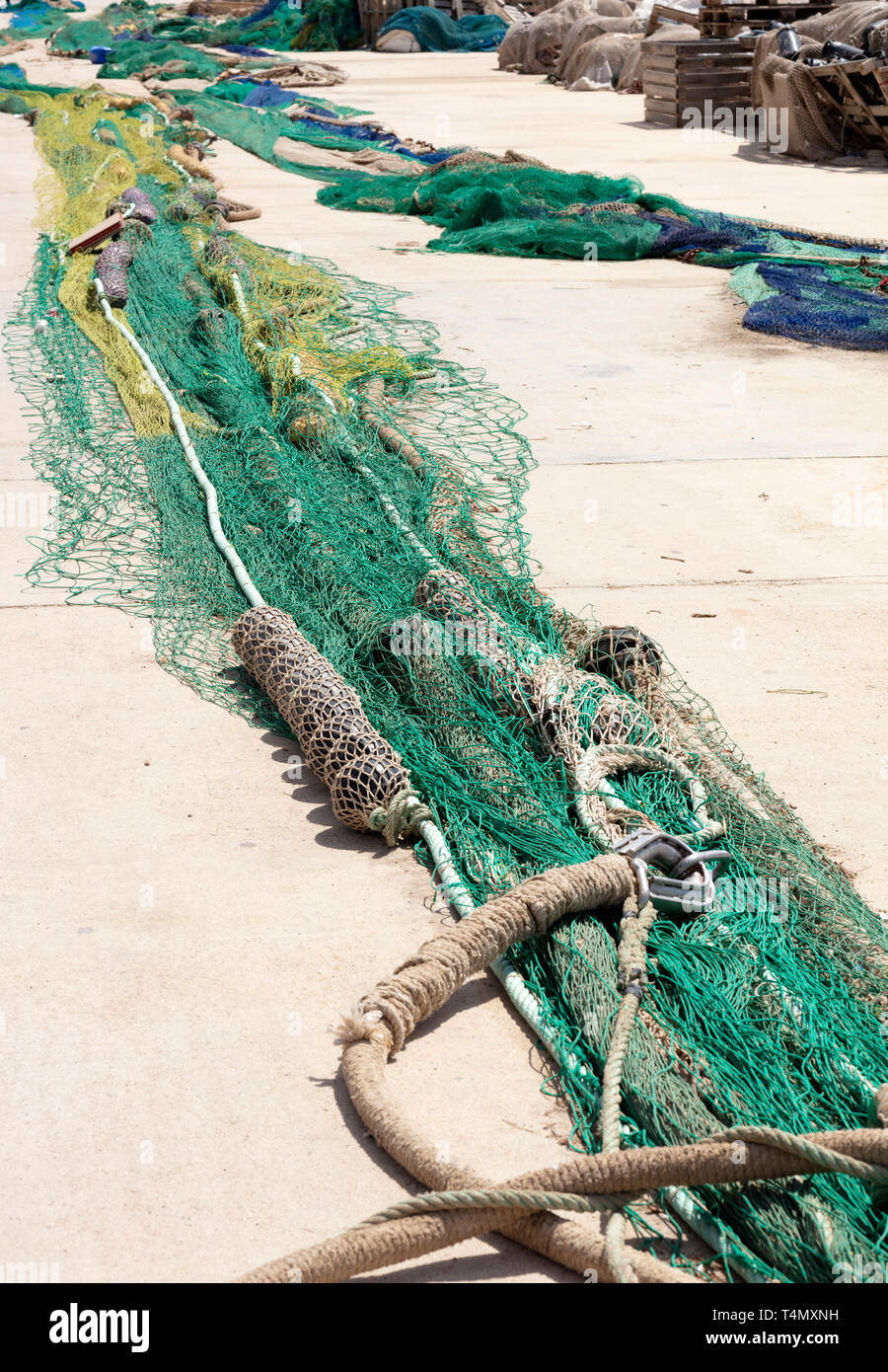 https://c8.alamy.com/comp/T4MXNH/fishing-nets-extended-in-the-port-to-be-revised-there-are-blue-and-green-with-wooden-boxes-in-the-background-T4MXNH.jpg