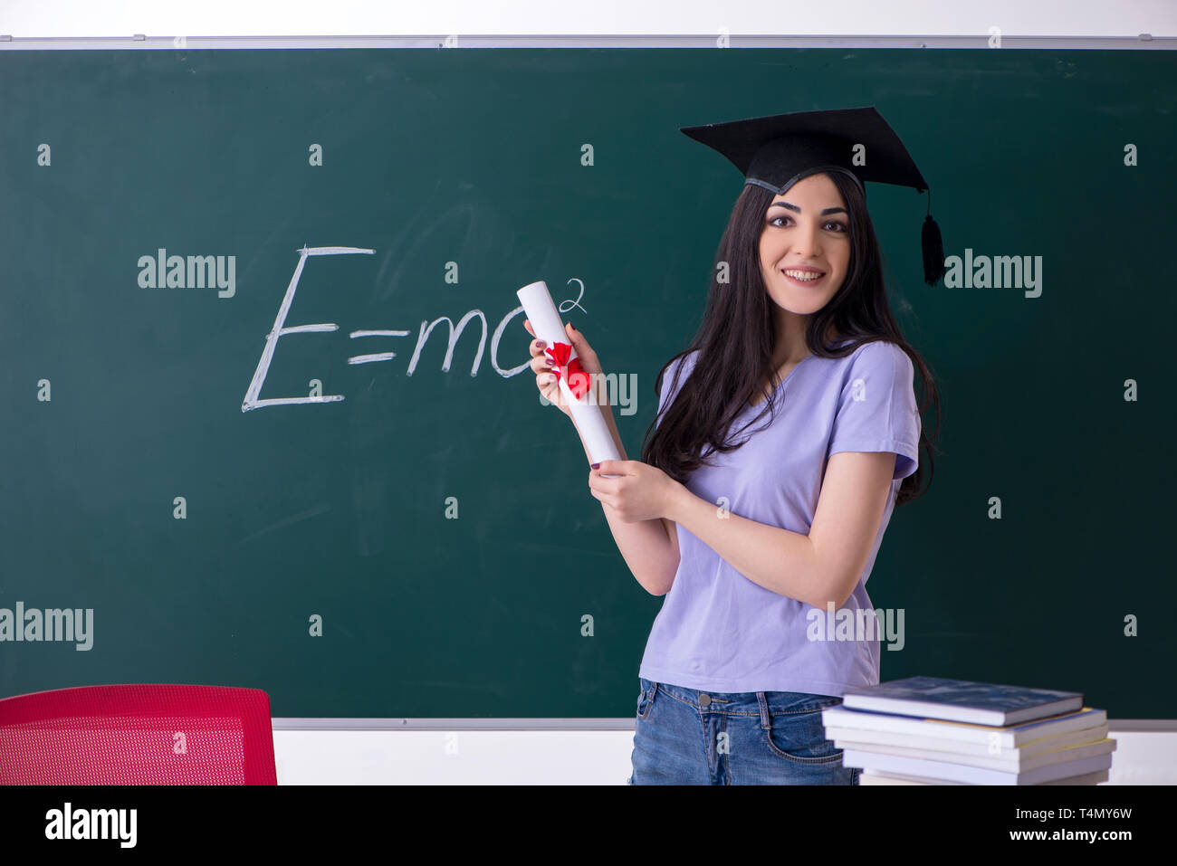 Female graduate student in front of green board Stock Photo - Alamy