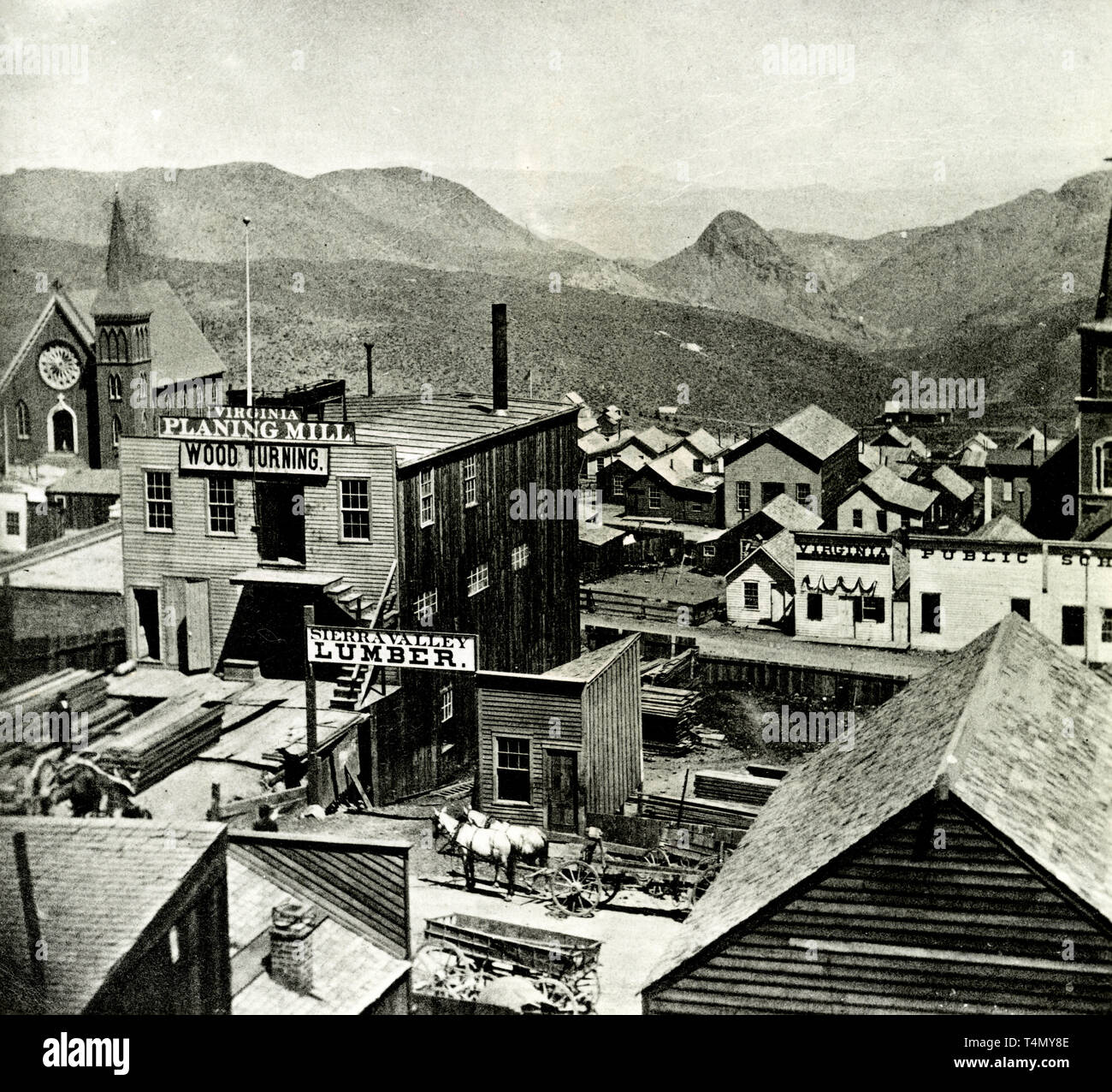 Photograph shows bird'seye view of church, lumber shop, planing mill