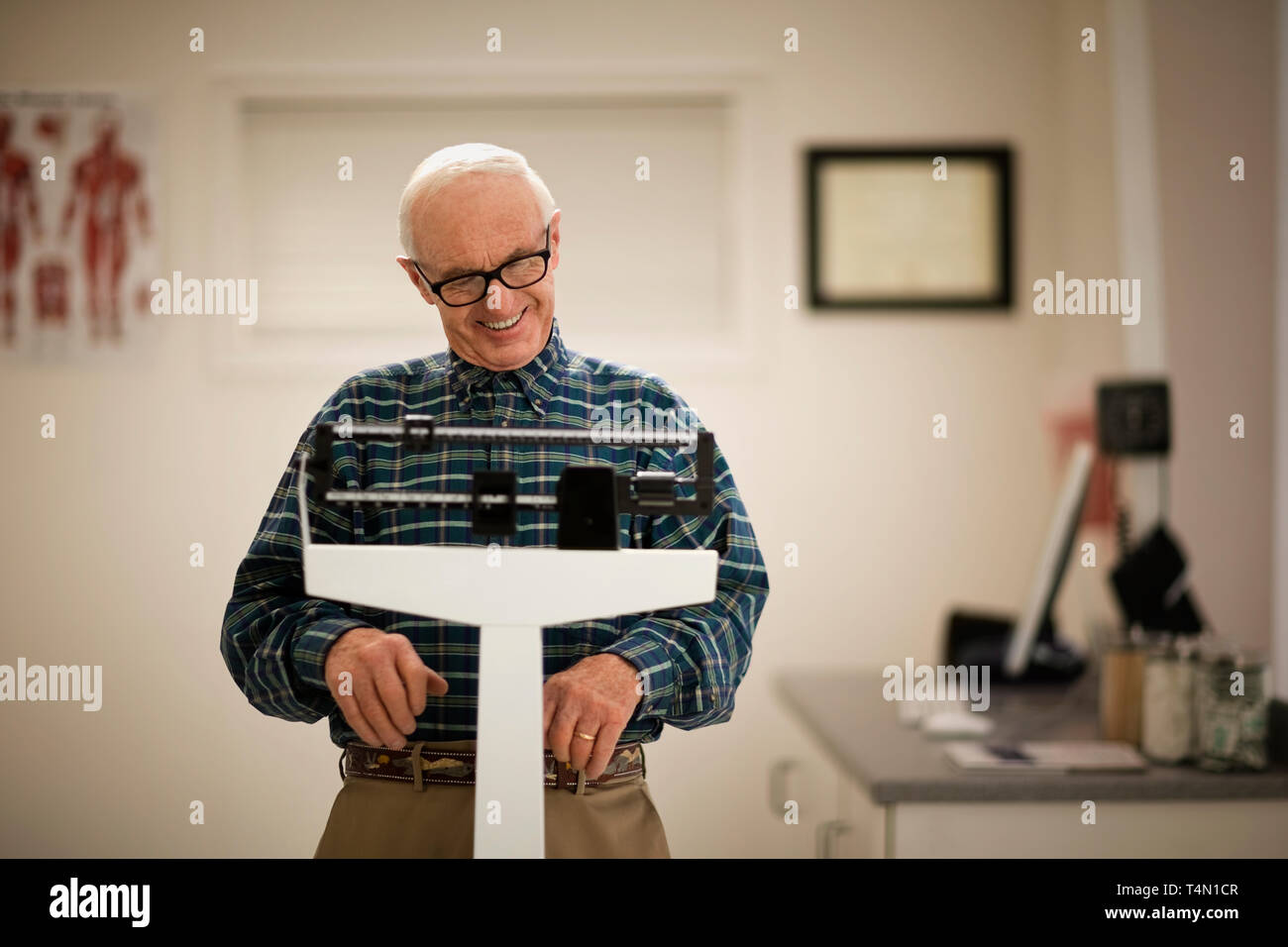 Senior man weighing himself on scales in a doctor's office. Stock Photo