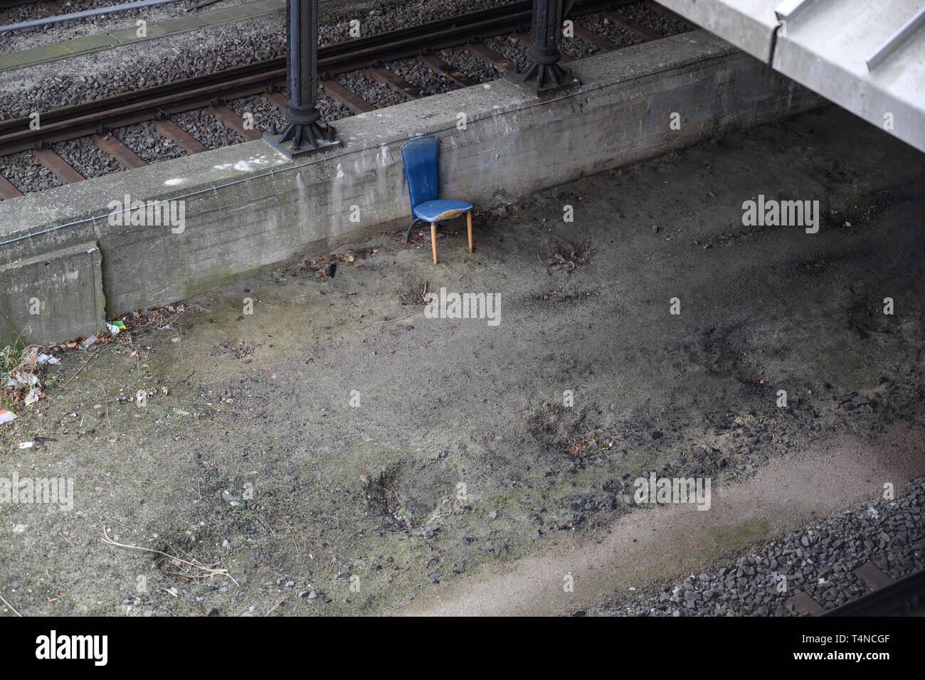 old blue chair next to the railway tracks at the freight station, home of the homeless, copy space Stock Photo