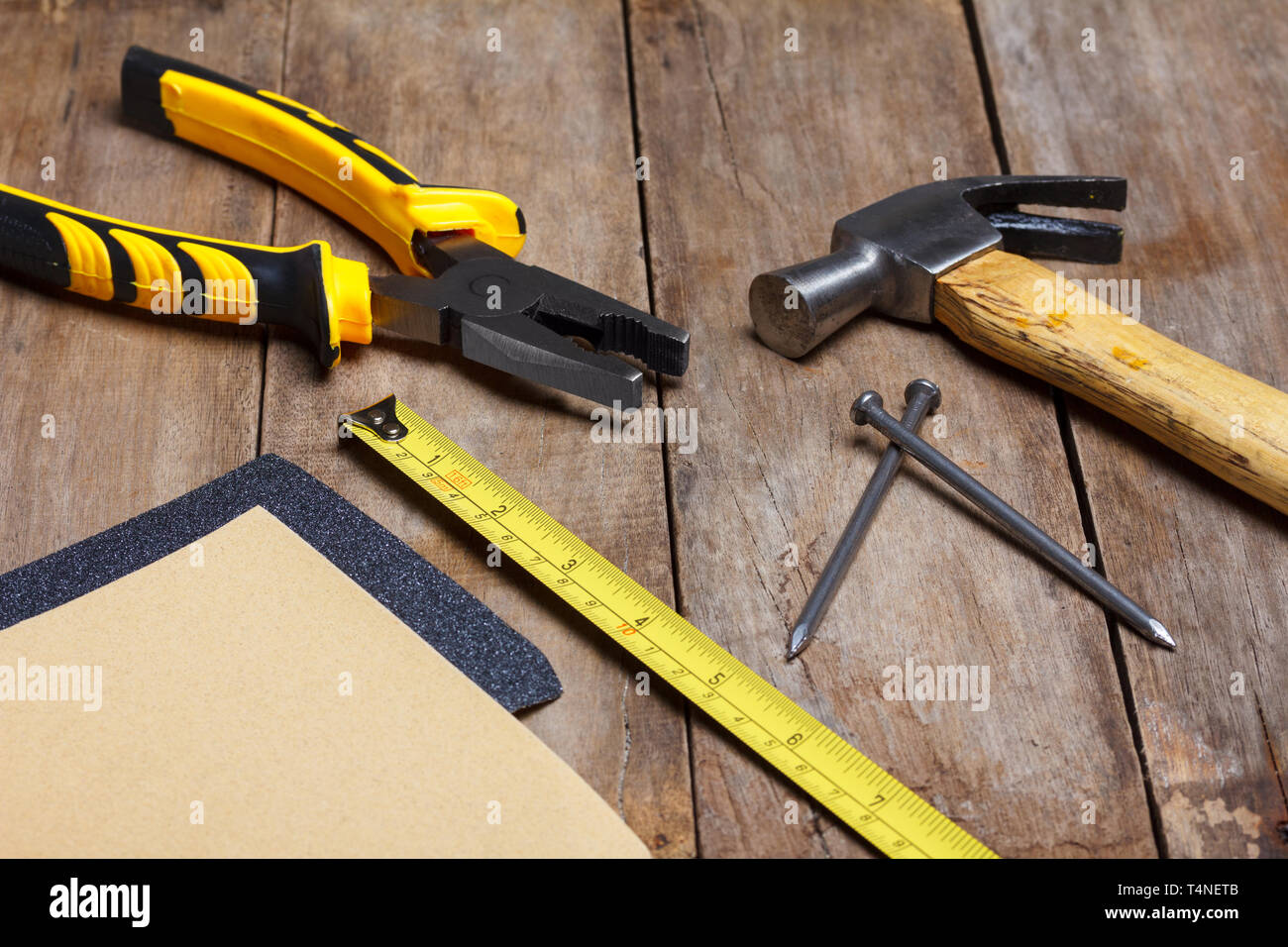Construction instruments on wooden table - sandpaper, pliers, measuring ...
