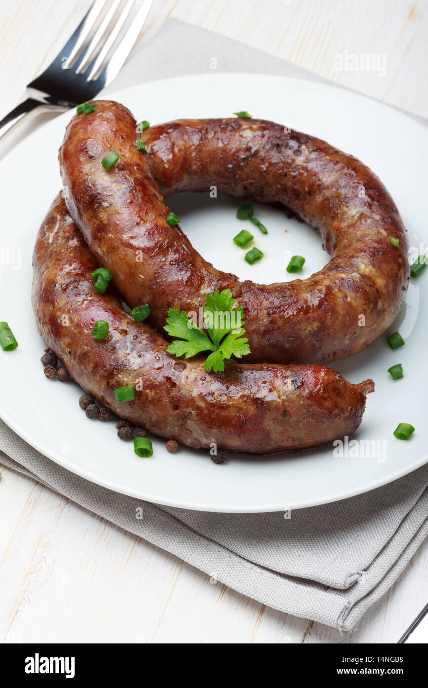 Traditional homemade coiled sausage on wooden table Stock Photo
