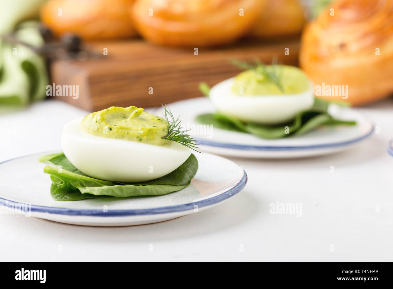 Deviled eggs with avocado and spinach and roll buns on festive Easter table, close up, selective focus Stock Photo