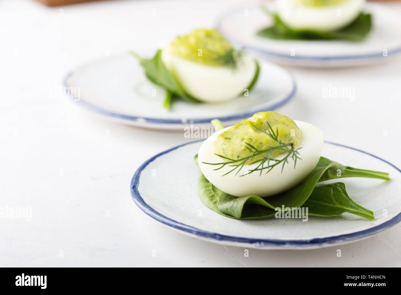 Deviled eggs with avocado and spinach on festive Easter table, close up, selective focus Stock Photo