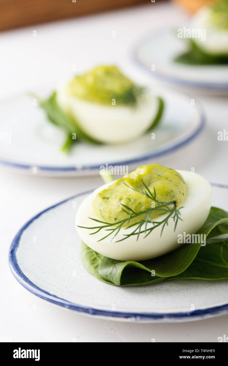 Deviled eggs with avocado and spinach on festive Easter table, close up, selective focus Stock Photo