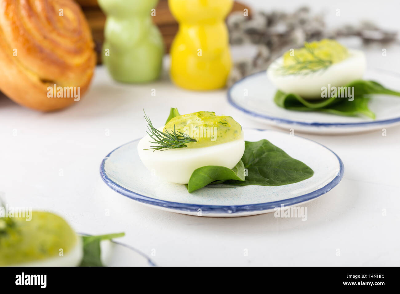 Deviled eggs with avocado and spinach and roll buns on festive Easter table, close up, selective focus Stock Photo