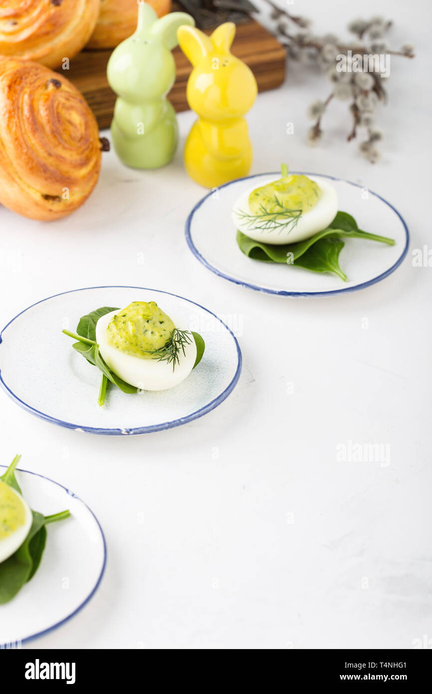 Deviled eggs with avocado and spinach and roll buns on festive Easter table, close up, selective focus Stock Photo