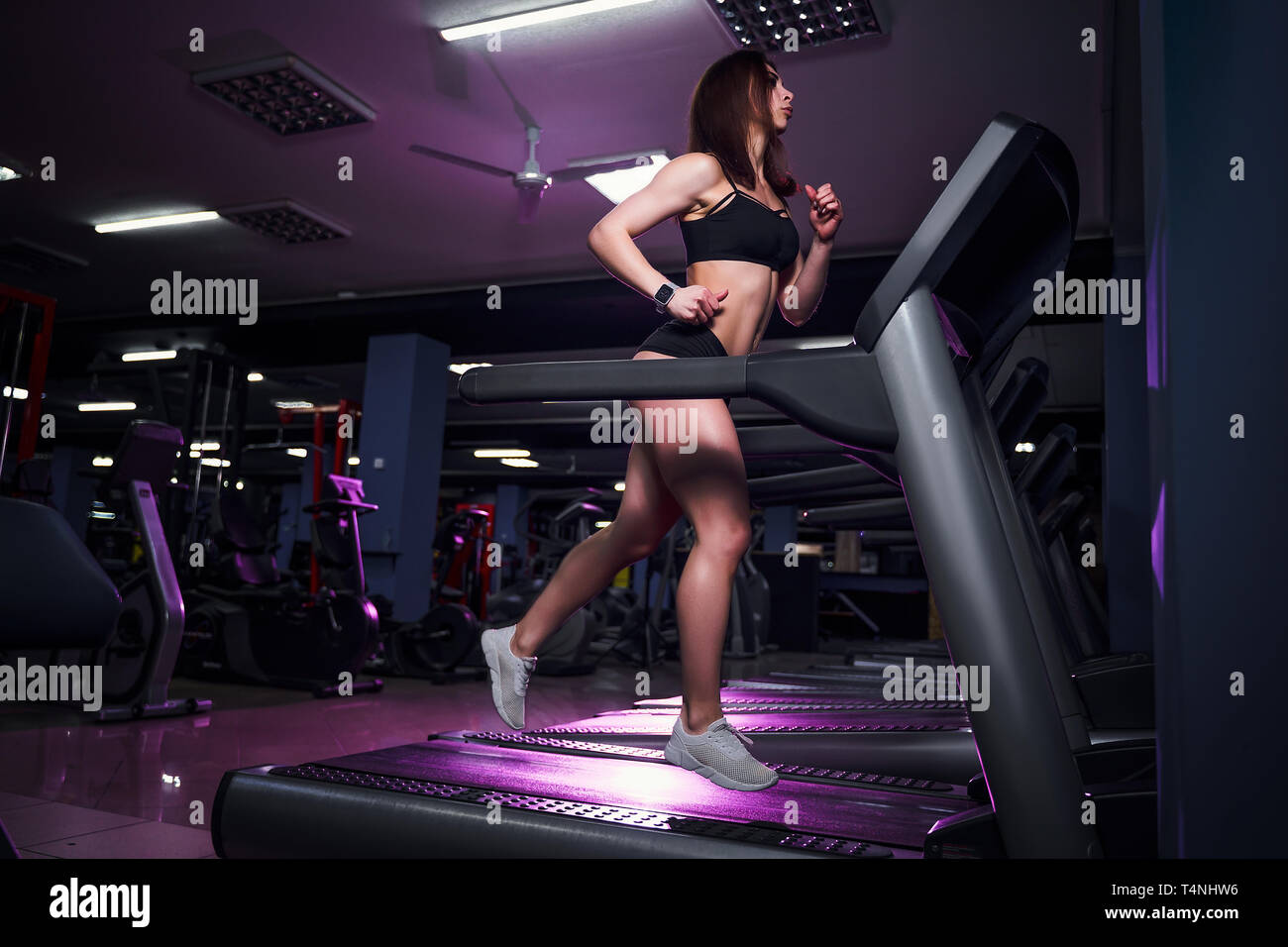 Active young woman and man running on treadmill in gym. Stock Photo