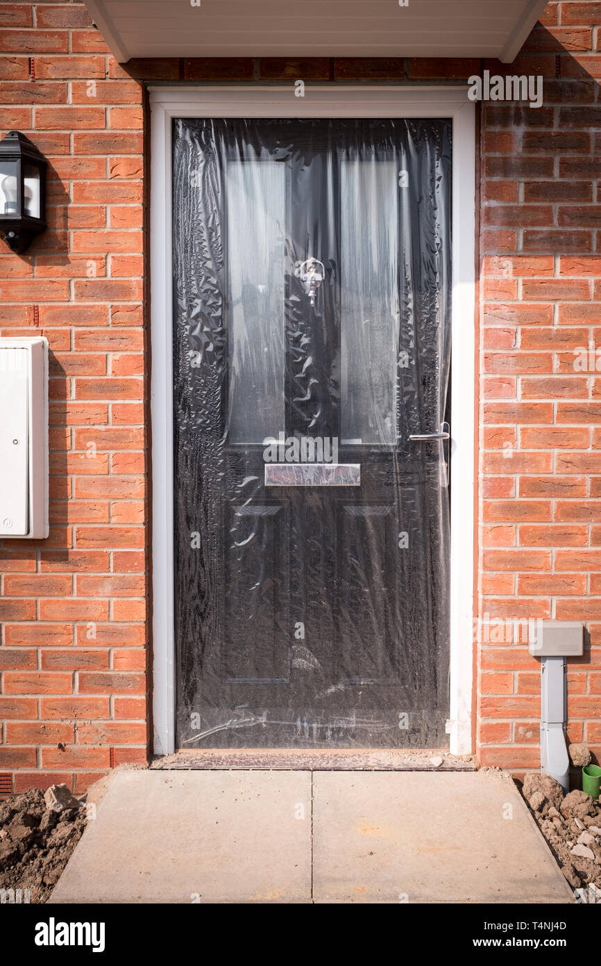 Front door of a brand new house, still wrapped in plastic sheeting Stock Photo