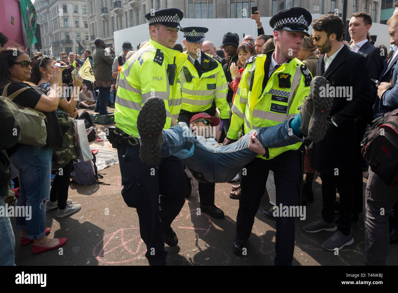 An activist with Extinction Rebellion is arrested during the London protest about climate change in a blocked-off Oxford Circus , on 17th April 2019, in London, England. Stock Photo