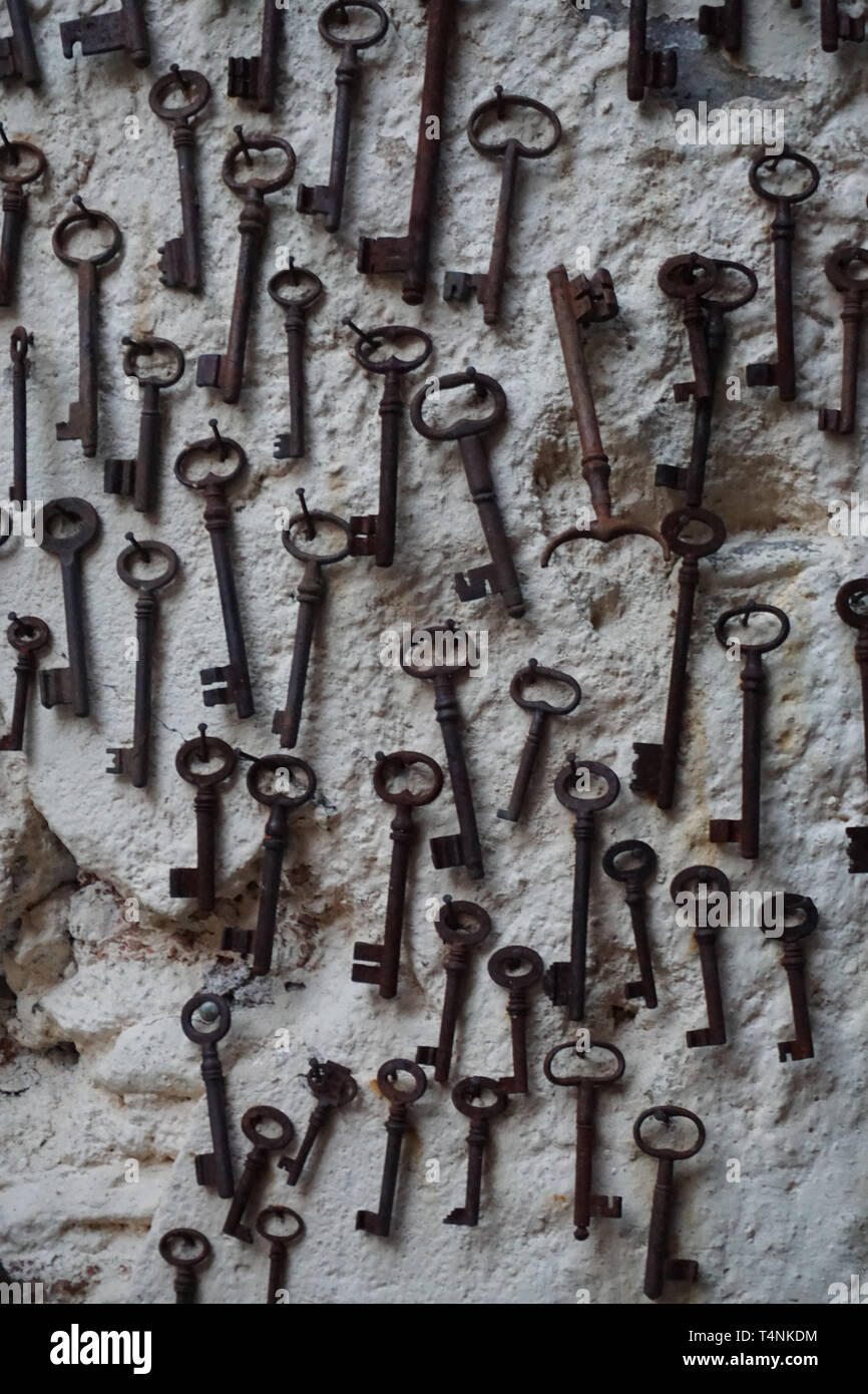 Photo of Bunch of antique keys hanging on brick wall black and white