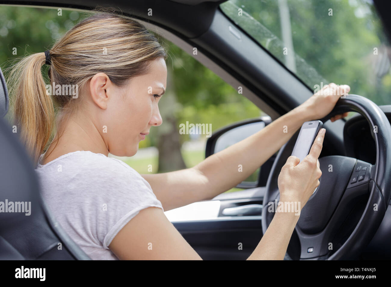 woman driving a car whilst using mobile phone Stock Photo