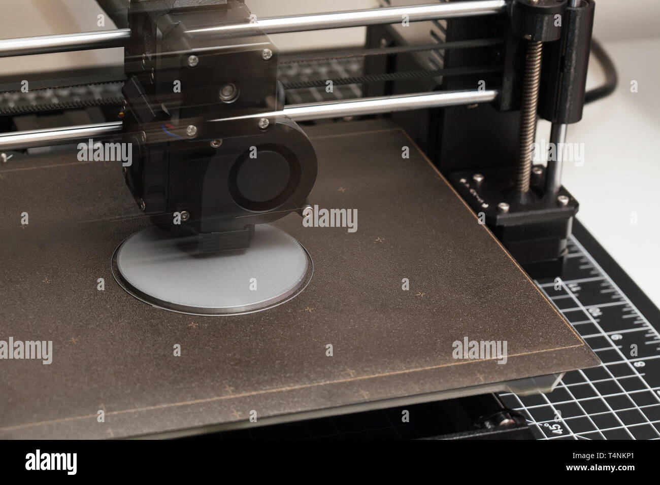 A closeup of a 3D printer in the process of printing a prototype design from a digital file while showing the extruder in motion. Stock Photo