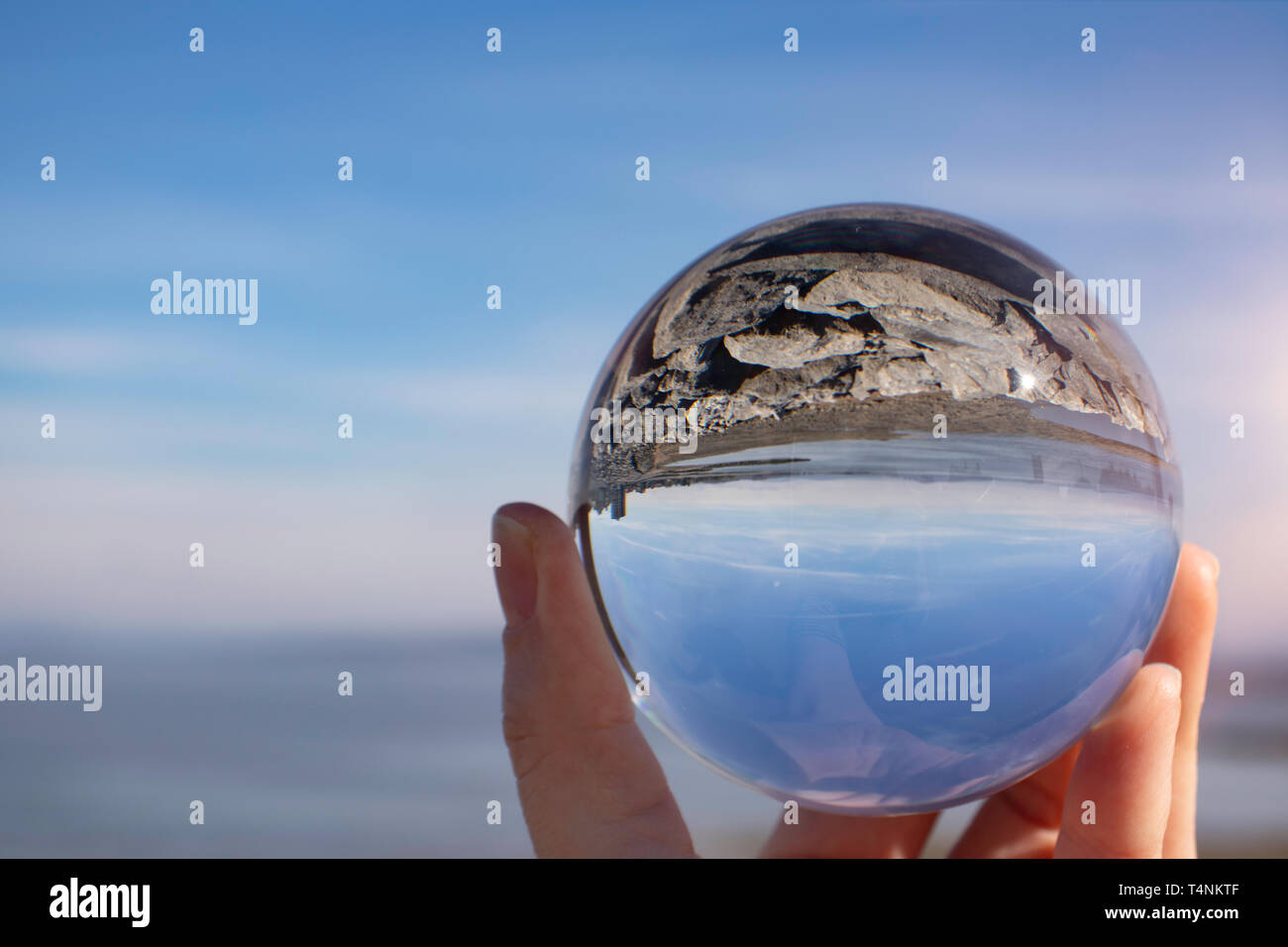 Morecambe Bay on a clear spring day, Lancashire UK, as seen through a crystal photography ball held in a female hand - refraction photography Stock Photo