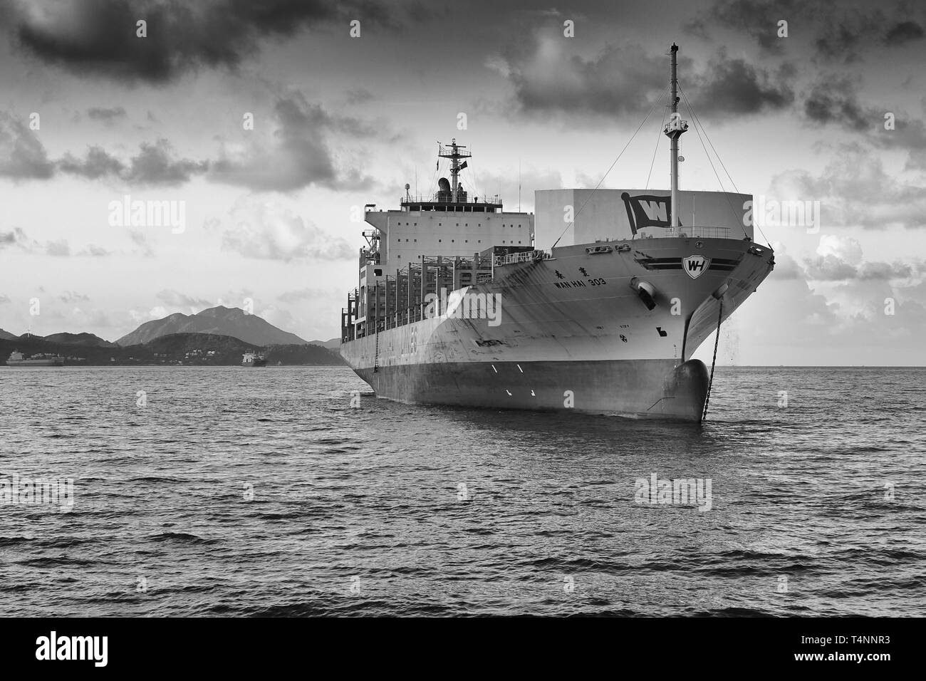 Black And White Photo Of The WAN HAI LINES Container Ship, WAN HAI 303, Anchored Off Green Island, Victoria Harbour, Hong Kong. Stock Photo