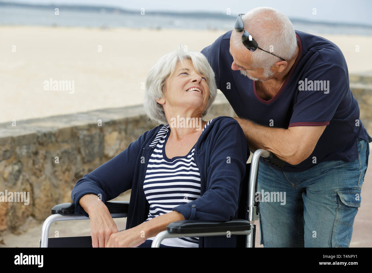 Elderly Man Talking Affectionately To His Wheelchair Bound Wife