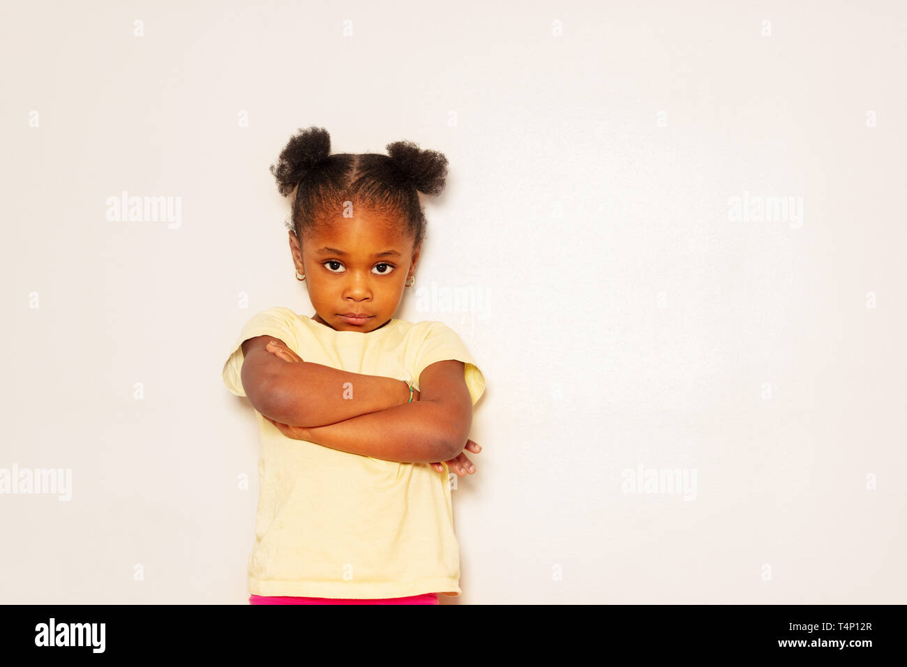 Sad And Discontent Little Girl Portrait Over Wall Stock Photo