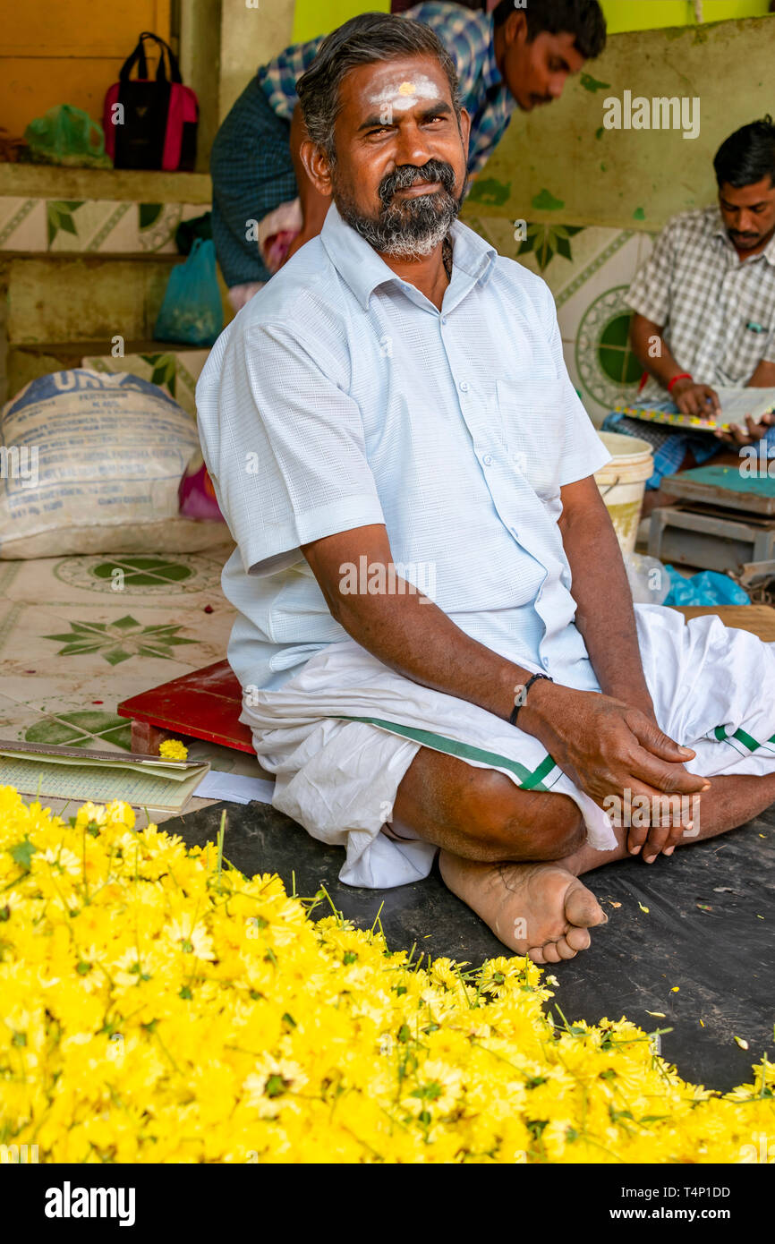 Vertical portrait of a man selling yellow marigolds at Mattuthavani flower market in Madurai, India. Stock Photo