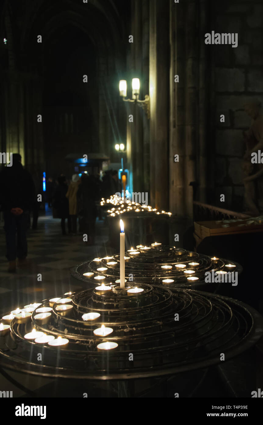Many candles on the background of people in the Cathedral of Notre Dame