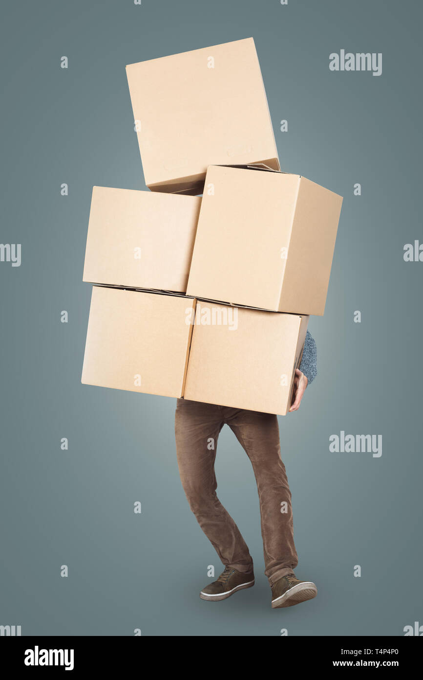 A man is carrying a big stack of cardboard boxes in his arms Stock Photo