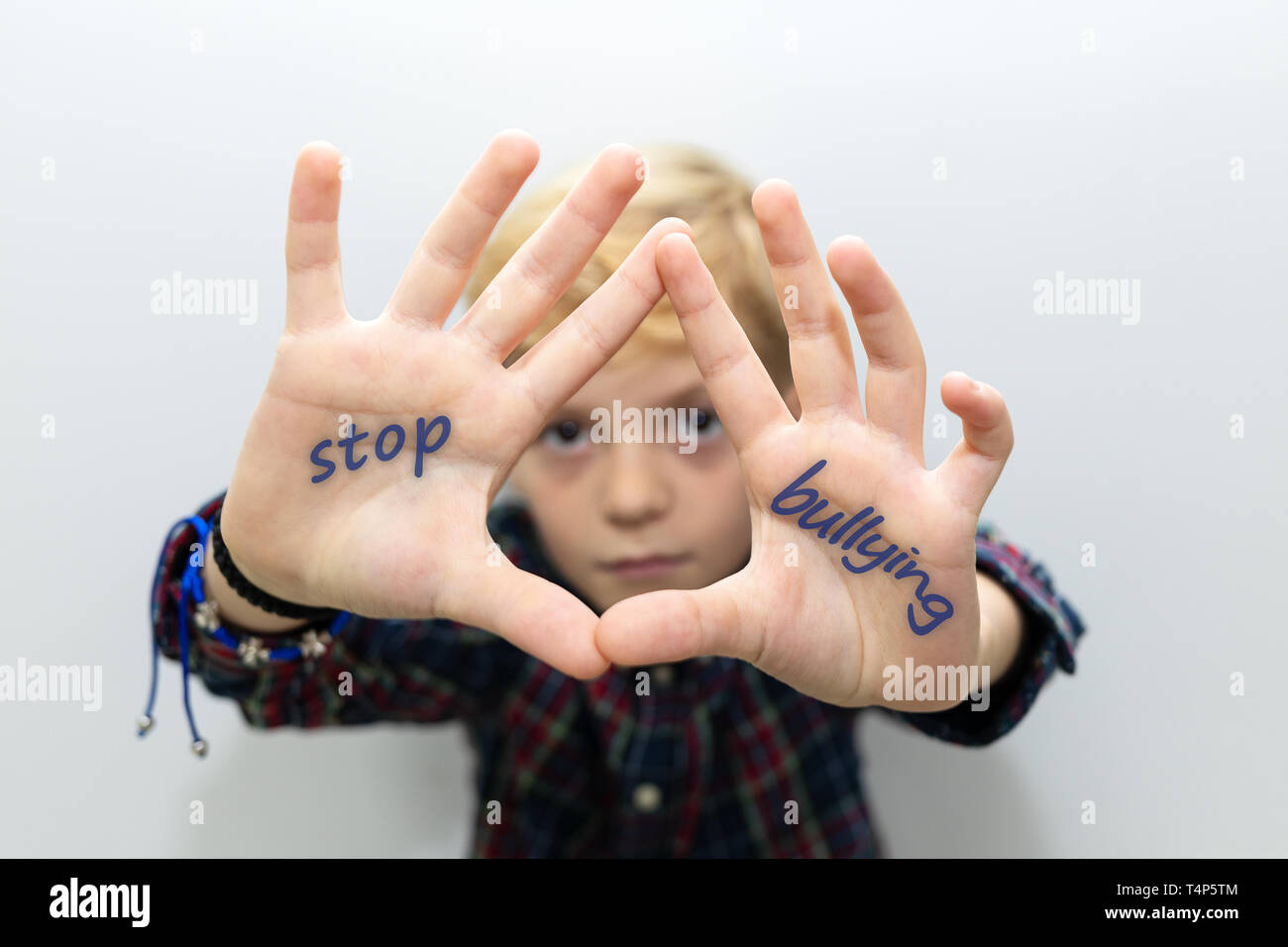 Sad little boy showing his hands with written text Stop bullying Stock Photo