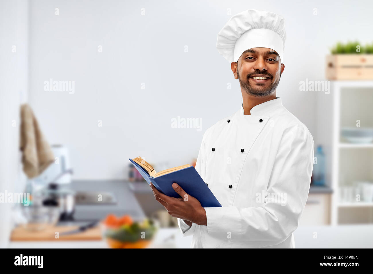 cooking, profession and people concept - happy male indian chef in toque  with cookbook over kitchen background Stock Photo - Alamy