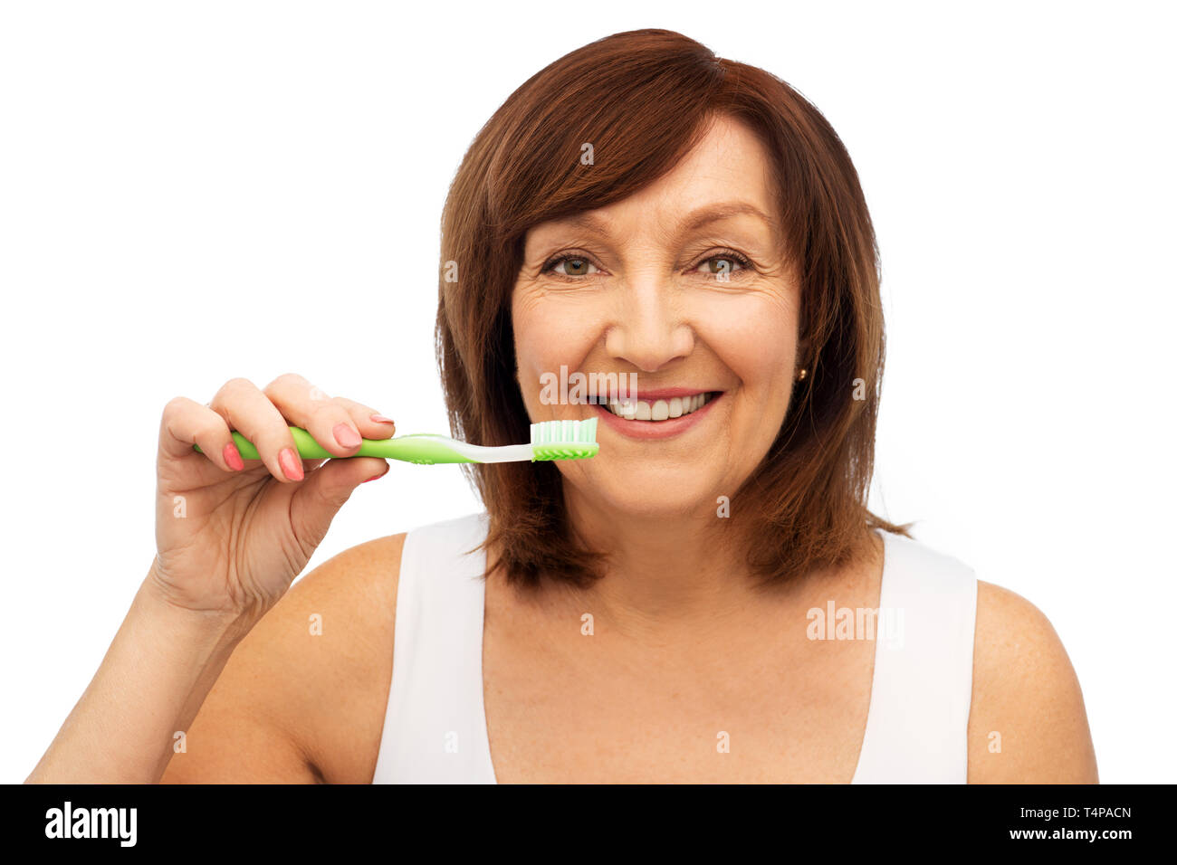 dental care and hygiene people concept - portrait of smiling senior woman with toothbrush brushing her teeth over white background Stock Photo