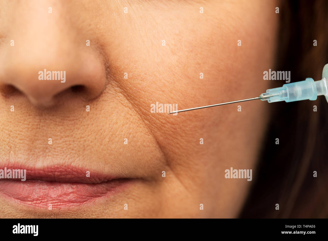 beauty, plastic surgery and cosmetology concept - close up of senior woman face and syringe Stock Photo