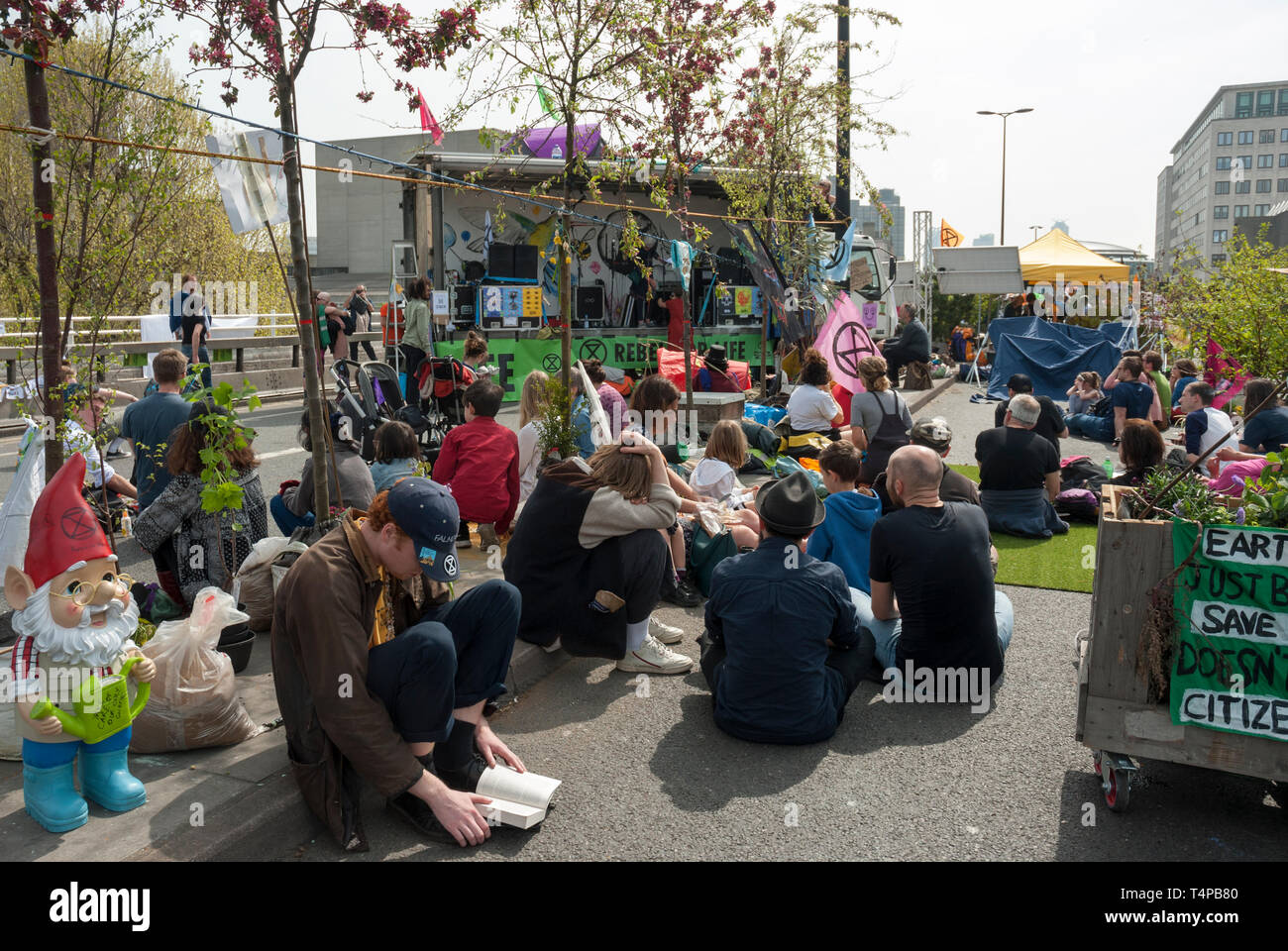 Extinction Rebellion protesters occupy Westminster bridge. Supporters sit listening to speeches from a stage regarding climate change. Stock Photo