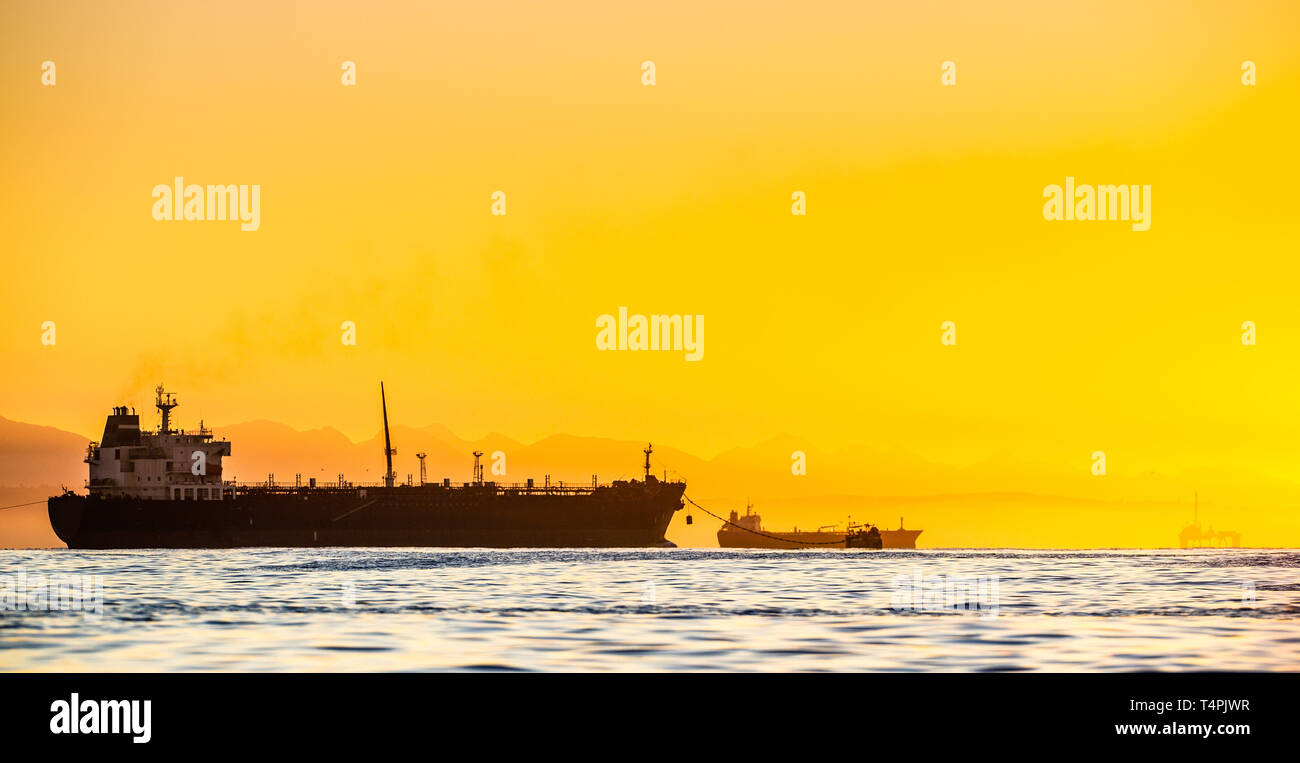 Oil tankers ship at sea on a background of sunset sky. Oil tankers in the ocean. Early in the morning, the sunrise sky. South Africa. Mossel Bay Stock Photo