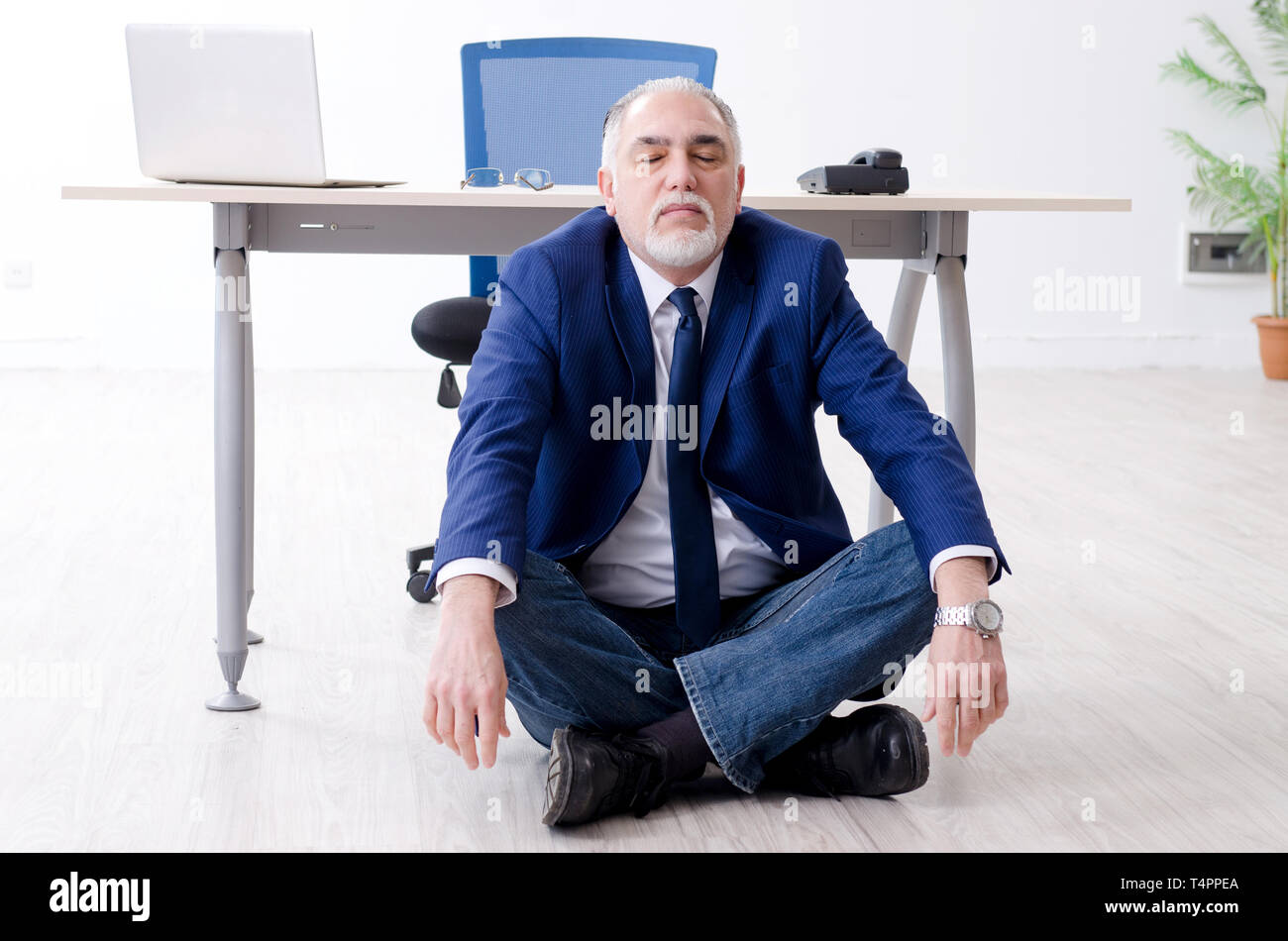 Aged businessman doing yoga exercises in the office Stock Photo - Alamy