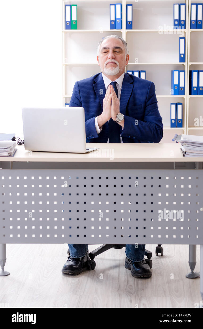 Aged businessman doing yoga exercises in the office Stock Photo - Alamy