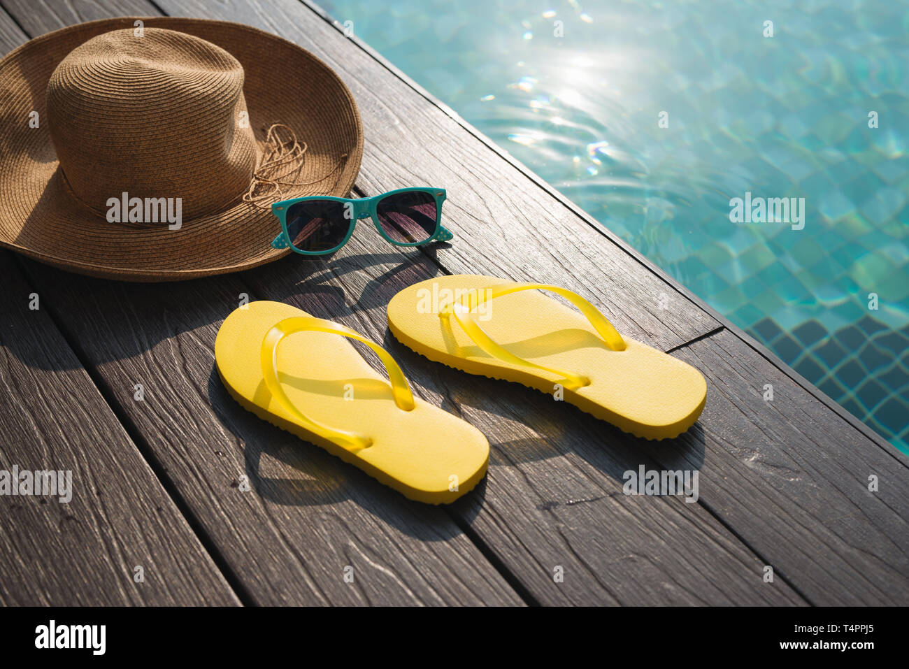 Hat, sunglasses and flip flops by swimming pool Stock Photo - Alamy
