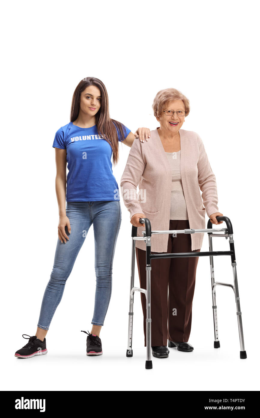 Full length portrait of a young woman volunteer helping a senior lady with a walker isolated on white background Stock Photo