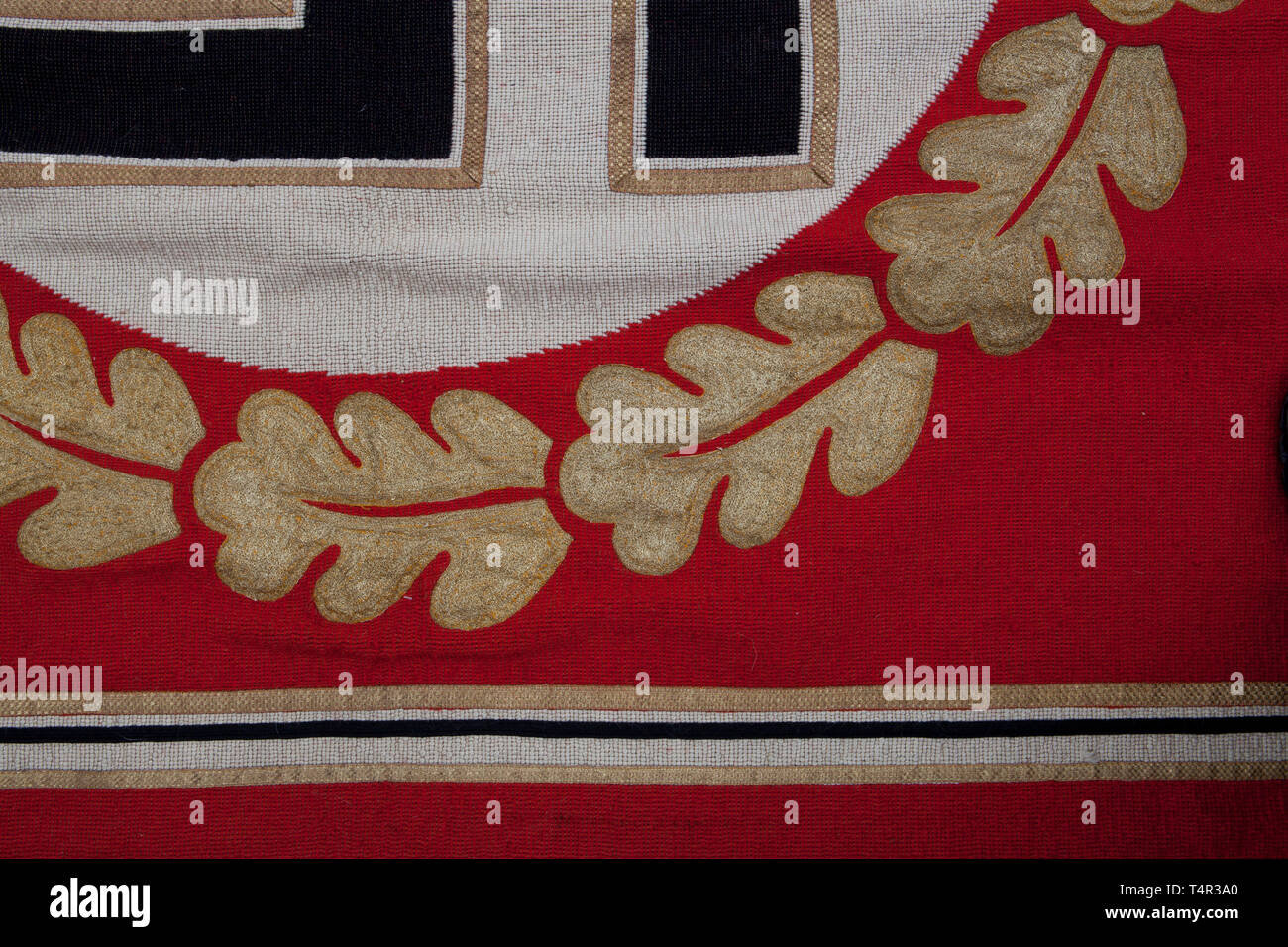 A Reich Chancellery tapestry From the New Reich's Chancellery in Berlin, heavy cotton construction, some soiling. Red field, with black-white border and gold edging. In centre, white disk with black swastika with gold trim, surrounded by gold-embroidered oak leaf wreath. Finished with gold fringe. Reverse covered in red cotton with tag embroidered 'RZM NSDAP der Obergebietsführer SA'. Upper edge with broad hem, inside a sleeve for wall hanging rod. Size 195 x 220 cm. See: Lt. Col. Thomas N. Johnson 'World War II German War Booty' Columbia 1982, p. 56 et seq. with illustrati, Editorial-Use-Only Stock Photo