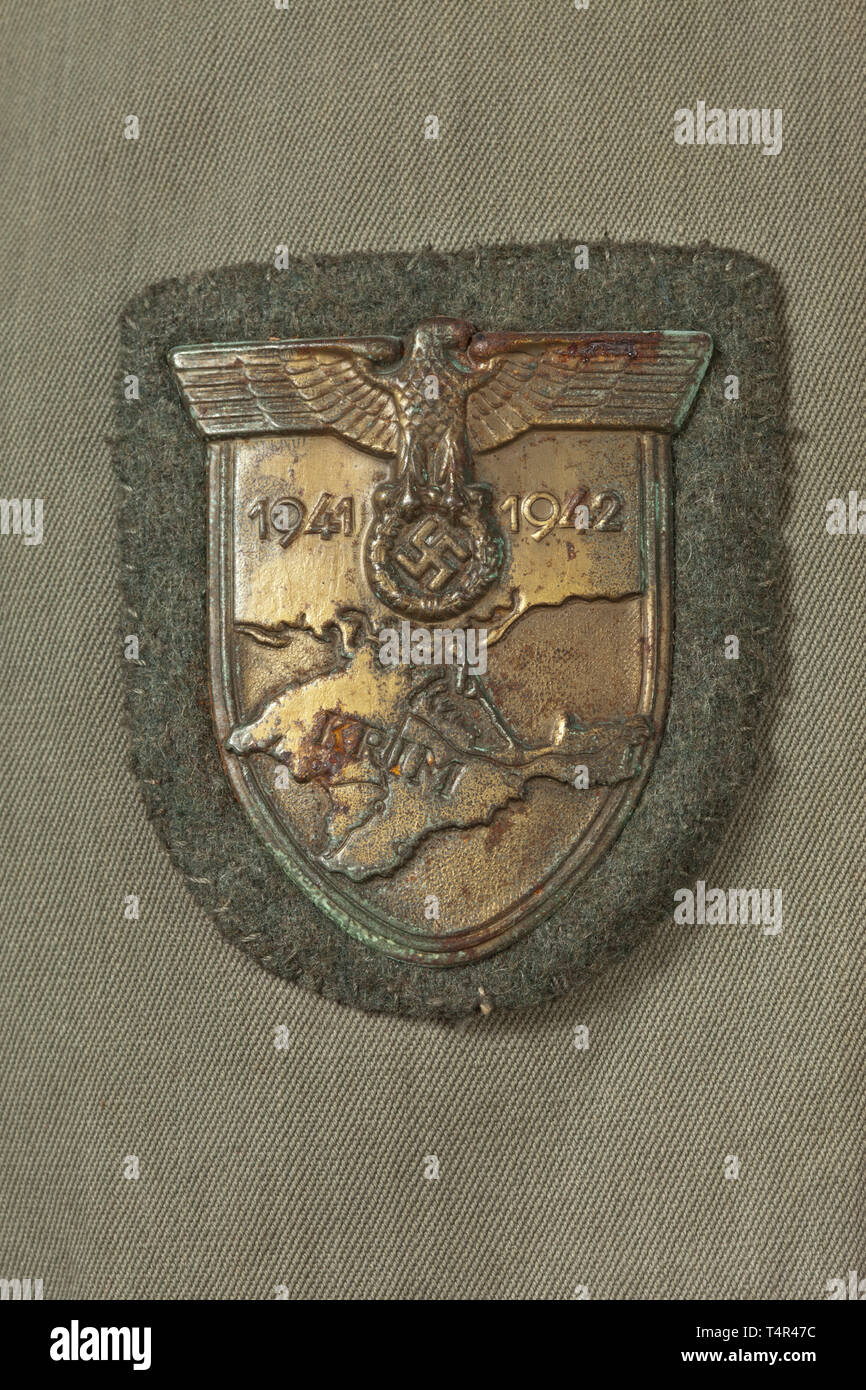 A field tunic for an Oberleutnant in Artillery Regiment 'Großdeutschland' Summer coat of field grey linen, in unlined issue with dark green collar and insignia for an officer. The shoulder boards with gold 'GD' appliqués, the cuff title in black velveteen with silver edge braid and silver-embroidered inscription 'Großdeutschland' in Sütterlin script. Stitched-on Krim Shield, affixed EK 1 and a Wound Badge in Black. An obviously used coat with storage-caused (oxidation) signs of age in never-cleaned condition. Included is the Soldbuch (Paybook) wi, Additional-Rights-Clearance-Info-Not-Available Stock Photo