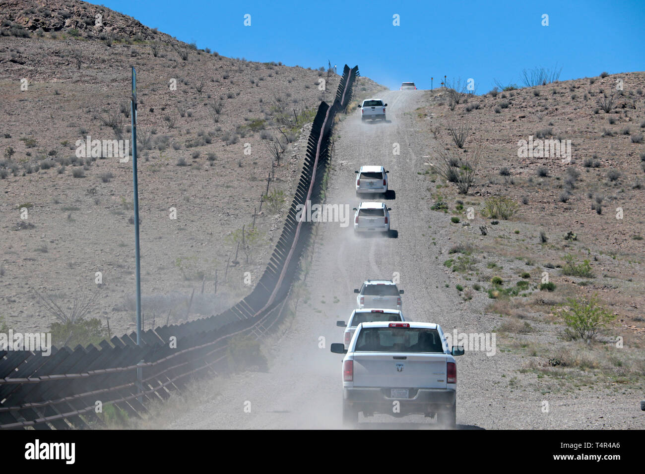 A caravan of vehicles with a team of U.S. Army Corps of Engineers employees and contractors drive along a long row of existing Normandy-style vehicle barrier near Columbus, New Mexico, April 11. USACE is supporting the Department of Homeland Security's request to build pedestrian fencing, construct and improve roads, and install lighting within the Yuma, Arizona, and El Paso, Texas, U.S. Border Patrol sectors following the Feb. 15 national emergency declaration on the southern border of the United States. The Department of Defense has the authority under Section 284 of Title 10, U.S. Code, to  Stock Photo