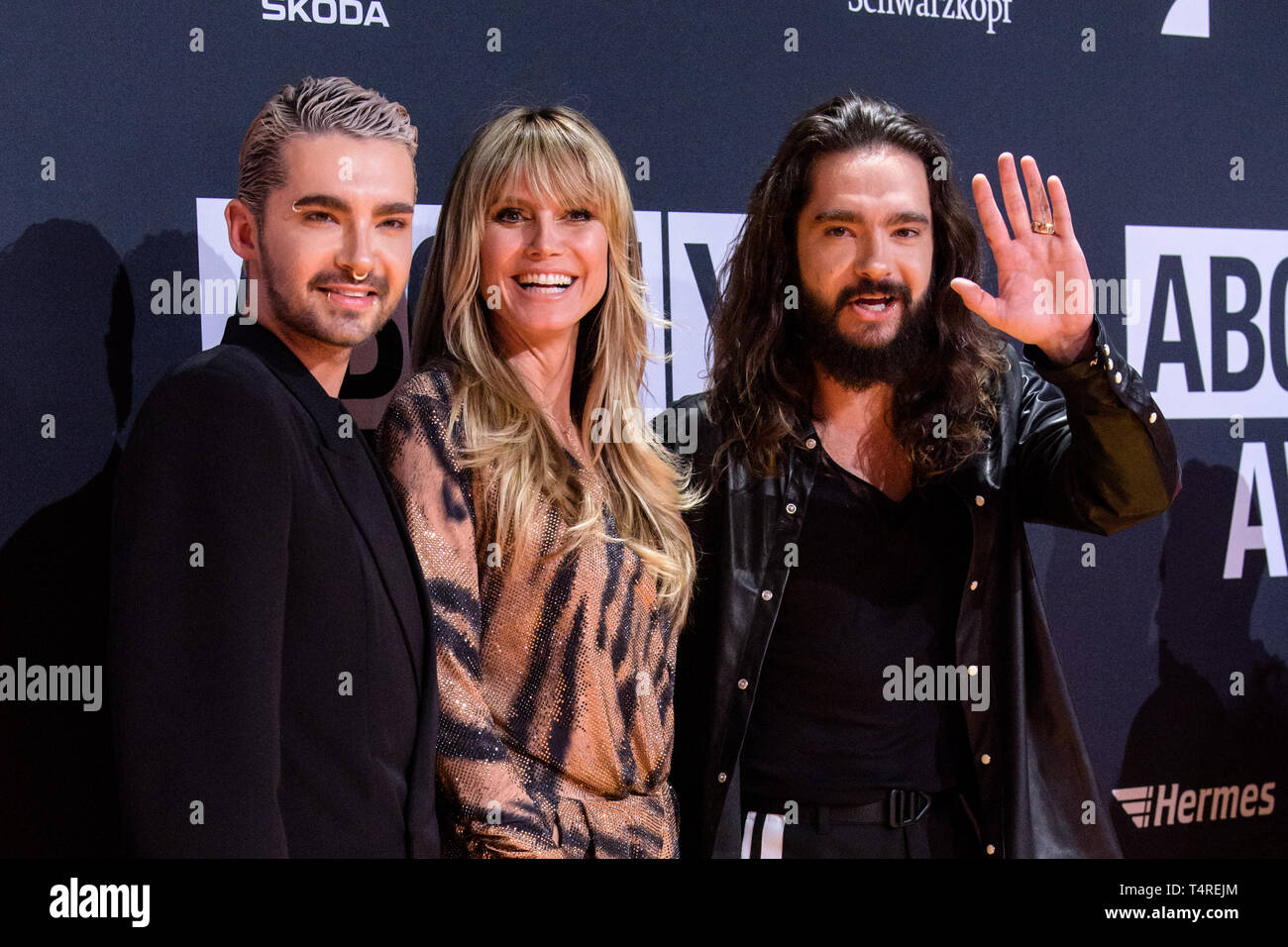 18 April 2019, Bavaria, Grünwald: Bill Kaulitz, singer of the band Tokio  Hotel (l-r), Heidi Klum, model, and her fiancé Tom Kaulitz, singer of the  band Tokio Hotel, come to the presentation