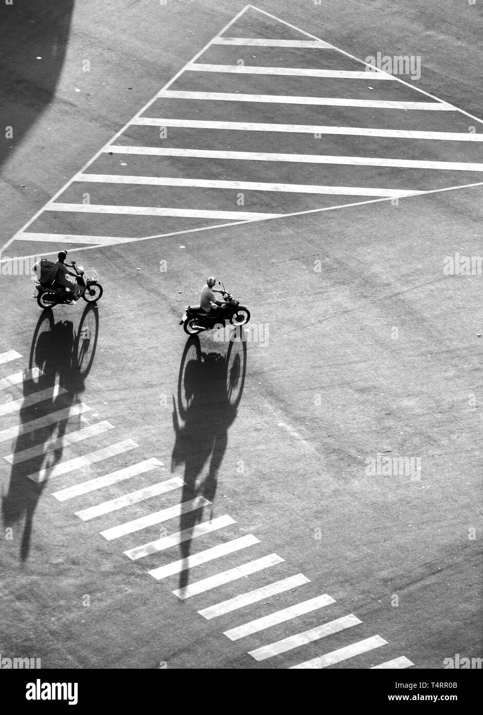 Amazing high view scene on street at Asian city, group of Vietnamese people ride motorcycles moving with shadow on road surface make impression shape Stock Photo