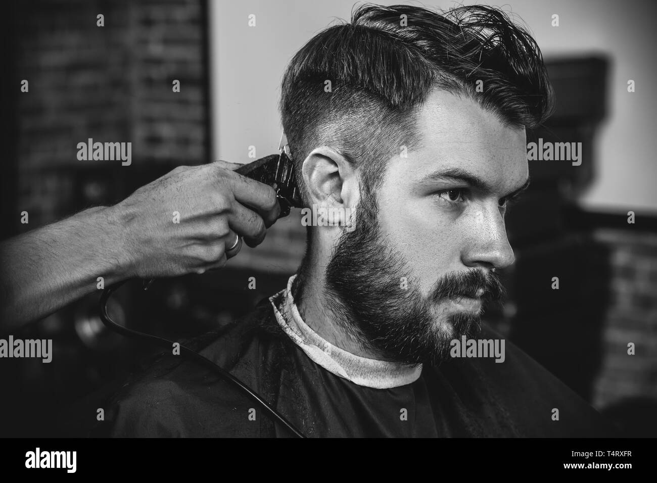 Young Handsome Barber Making Haircut For Attractive Bearded Man At